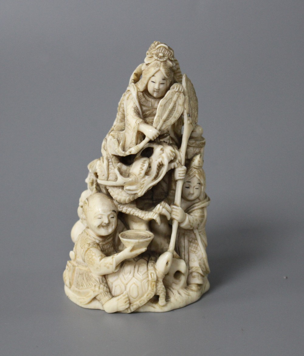 A Japanese Meiji period carved ivory group of a goddess and dragon with attendants, signed to the underside, height 8cm